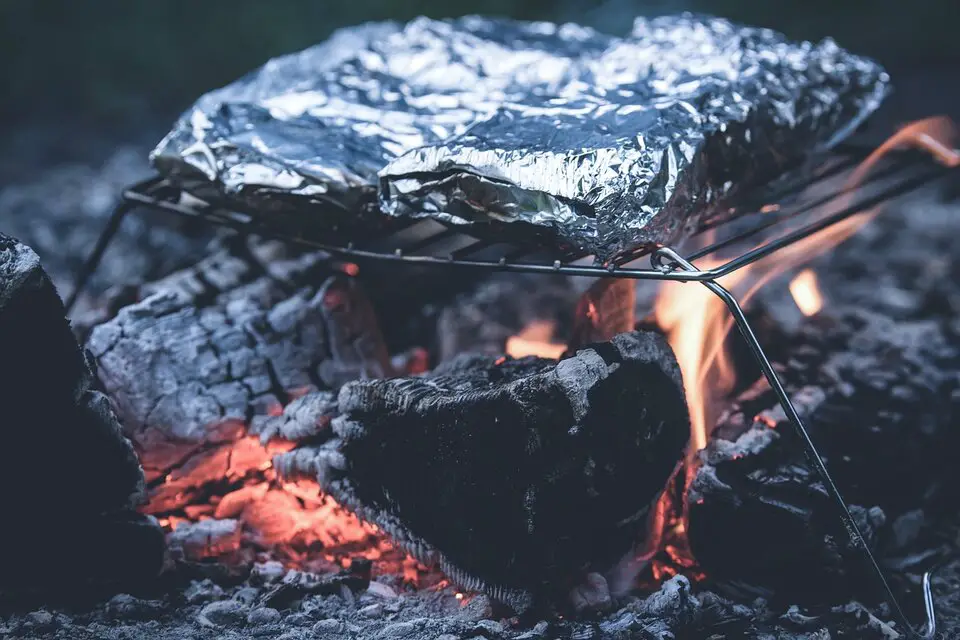 aluminum foil wrapped meal cooking on campfire grill